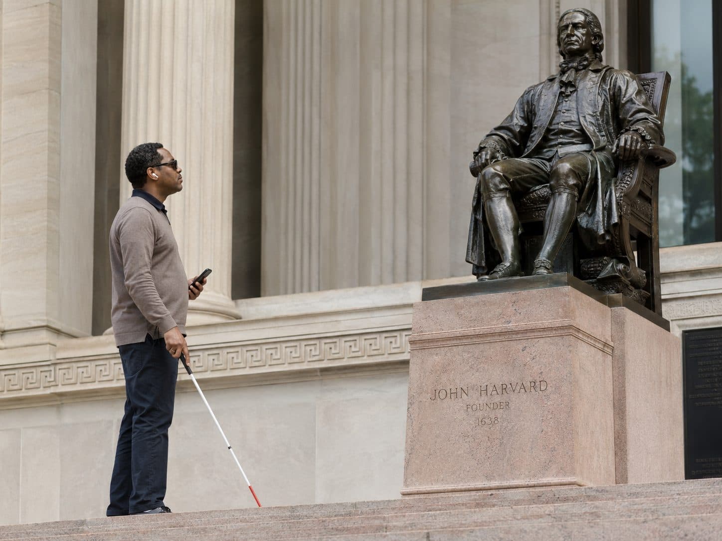 A visitor with a cane listening near a historic statue, showing a more inclusive self-guided experience.
